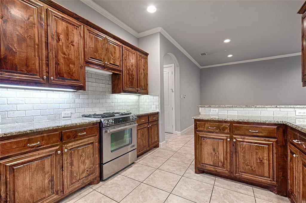 8329 Moore Street Frisco, TX 75034 - Photo 11 of 30 Kitchen featuring stainless steel gas range oven, light stone counters, ornamental molding, recessed lighting, and arched walkways