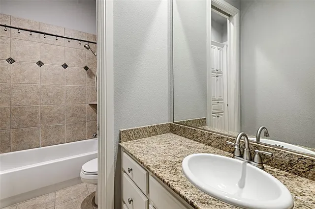 a bathroom with a granite countertop sink a toilet and bathtub