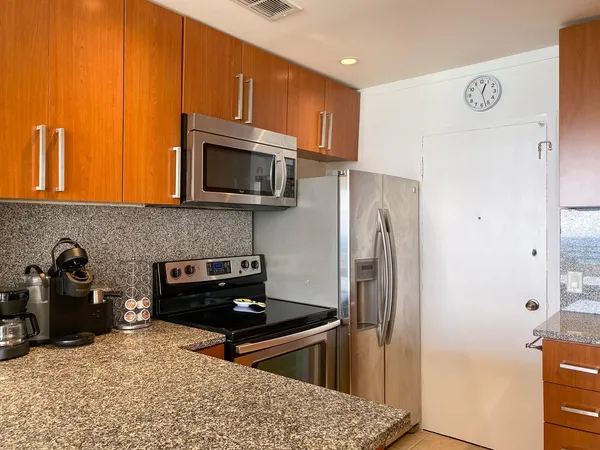 a kitchen with stainless steel appliances granite countertop a refrigerator and a stove top oven