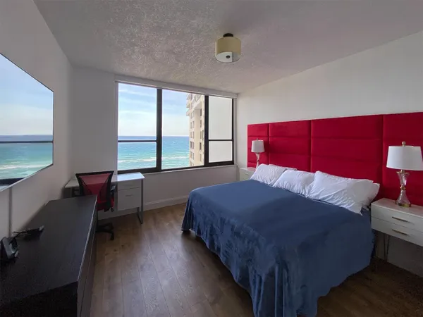 a bedroom with a bed a desk and chair with window