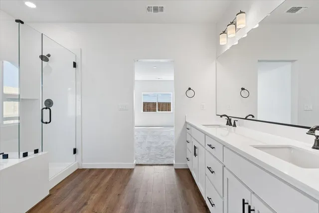 a spacious bathroom with a double vanity sink a mirror and shower
