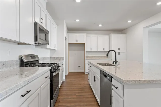 a kitchen with stainless steel appliances granite countertop a stove a sink dishwasher and a microwave oven with white cabinets