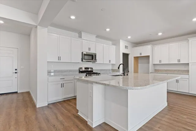 a kitchen with stainless steel appliances white cabinets a sink a stove a refrigerator and cabinets