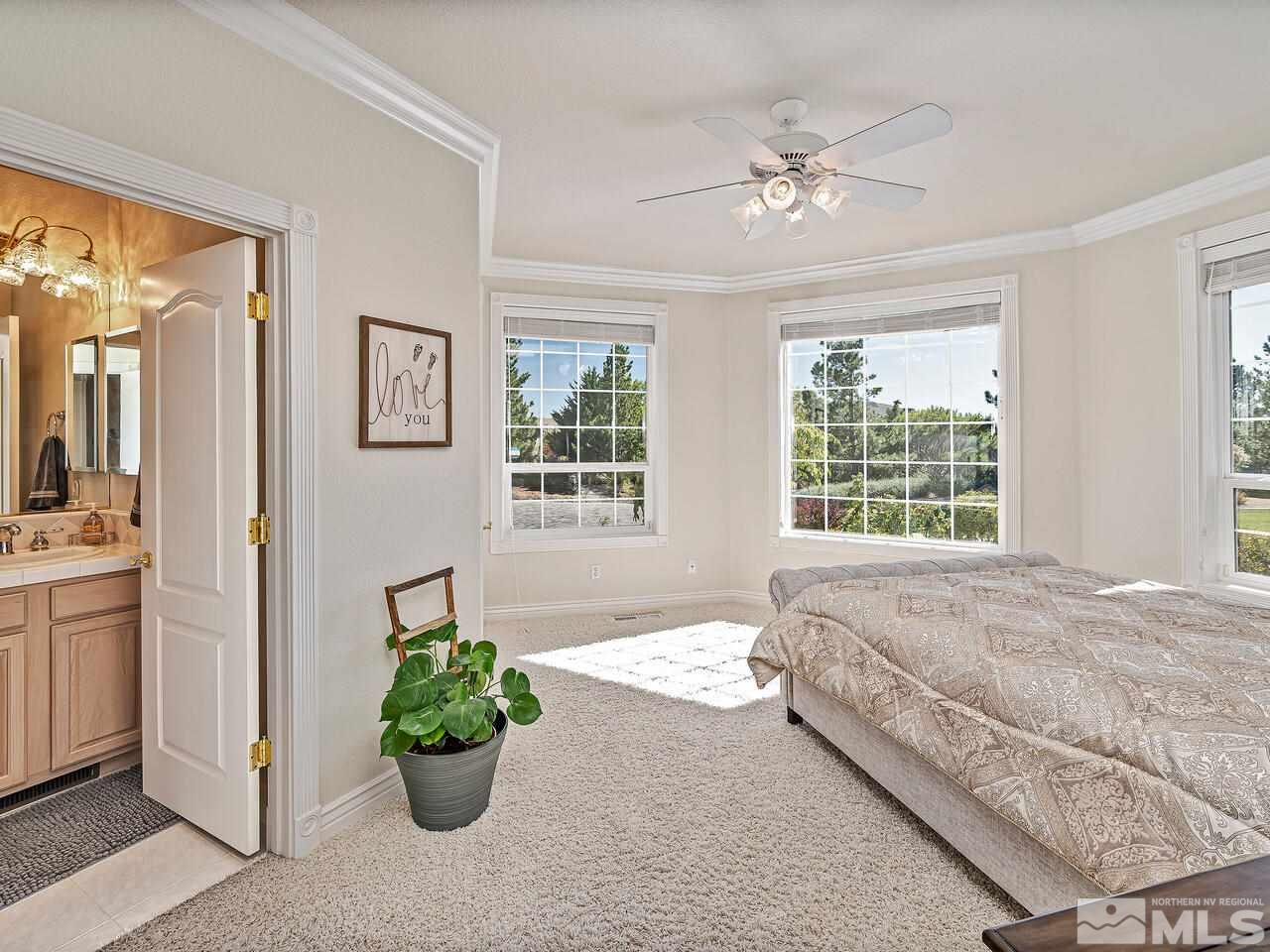 13215 West Saddlebow Drive Reno, NV 89511 - Photo 16 of 32 a bed sitting in a spacious bedroom next to a window and a chandelier