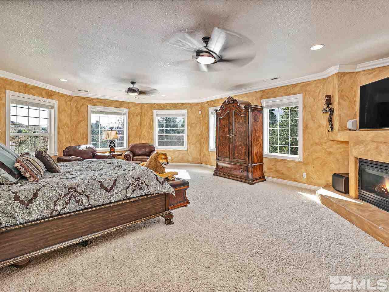13215 West Saddlebow Drive Reno, NV 89511 - Photo 18 of 32 a spacious bedroom with a large bed a flat screen tv and windows