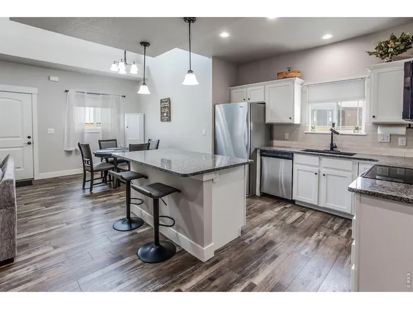 a kitchen with stainless steel appliances kitchen island granite countertop a table chairs sink and cabinets