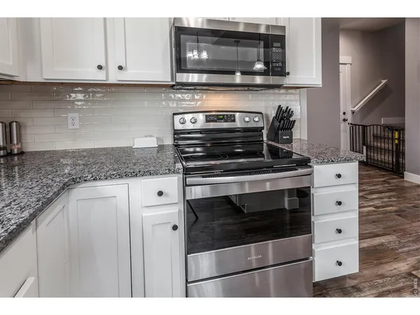 a kitchen with granite countertop a stove microwave and cabinets