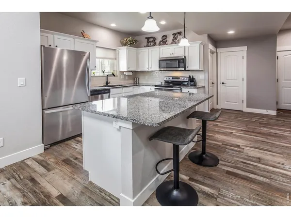 a kitchen with kitchen island a refrigerator a stove a sink and a oven with wooden floor