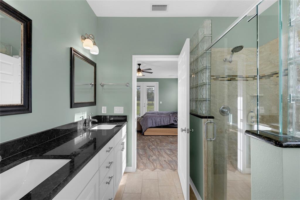 5608 Strong Point Weirsdale, FL 32195 - Photo 24 of 71 a bathroom with a granite countertop sink a mirror and shower