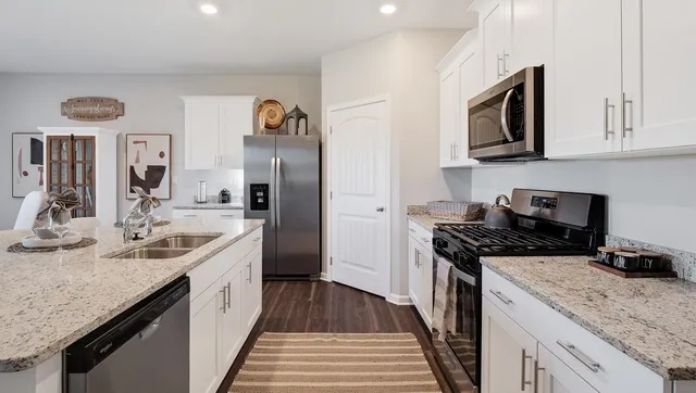 a kitchen with a sink appliances cabinets and wooden floor