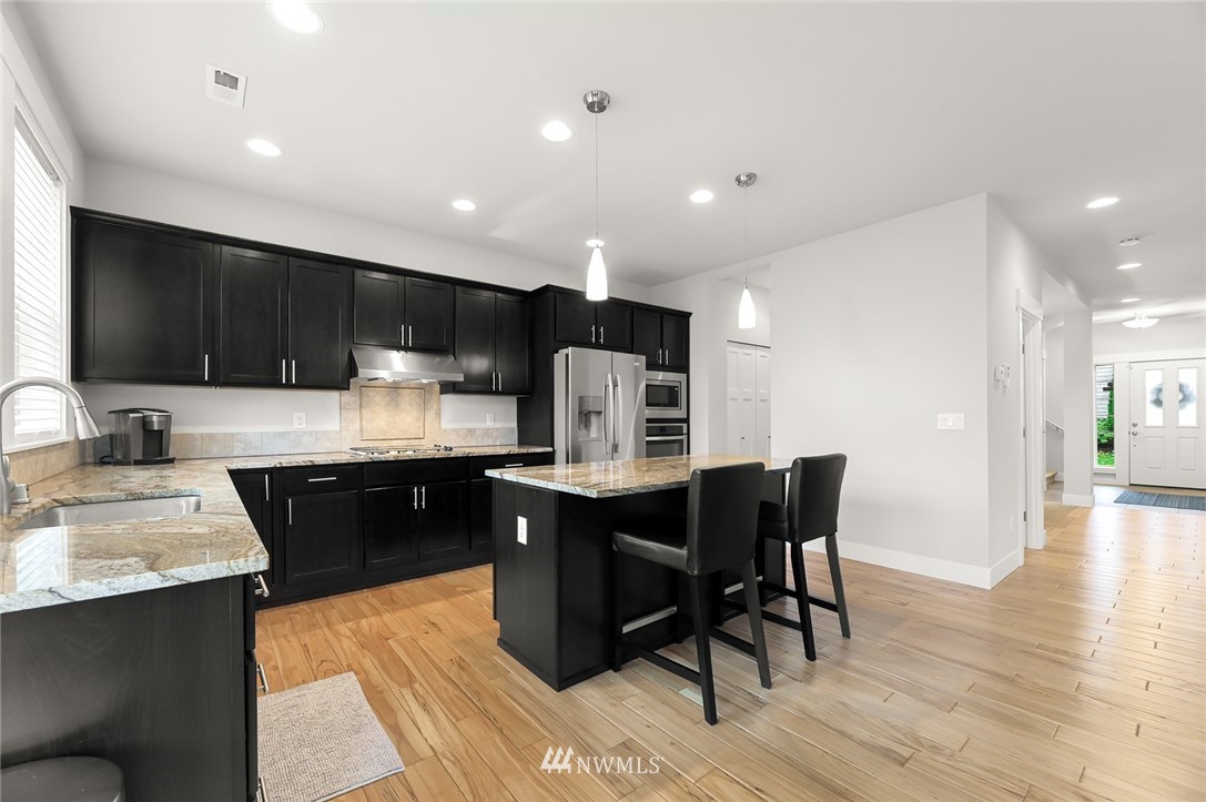 1017 Chelan Place Northeast Renton, WA 98059 - Photo 12 of 40 a kitchen with stainless steel appliances granite countertop wooden cabinets a refrigerator a sink a stove a dining table and chairs