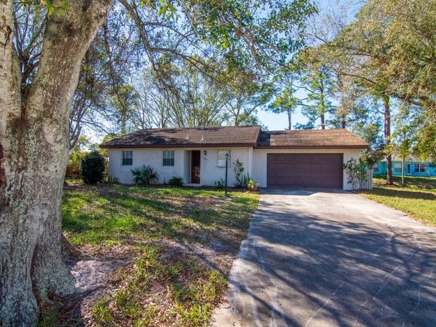 a front view of a house with a garden and trees
