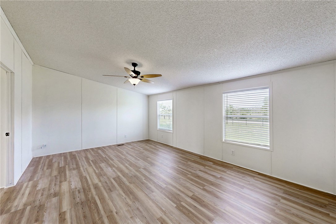 11459 Winstead Lane Calvert, TX 77837 - Photo 18 of 37 an empty room with wooden floor chandelier fan and windows