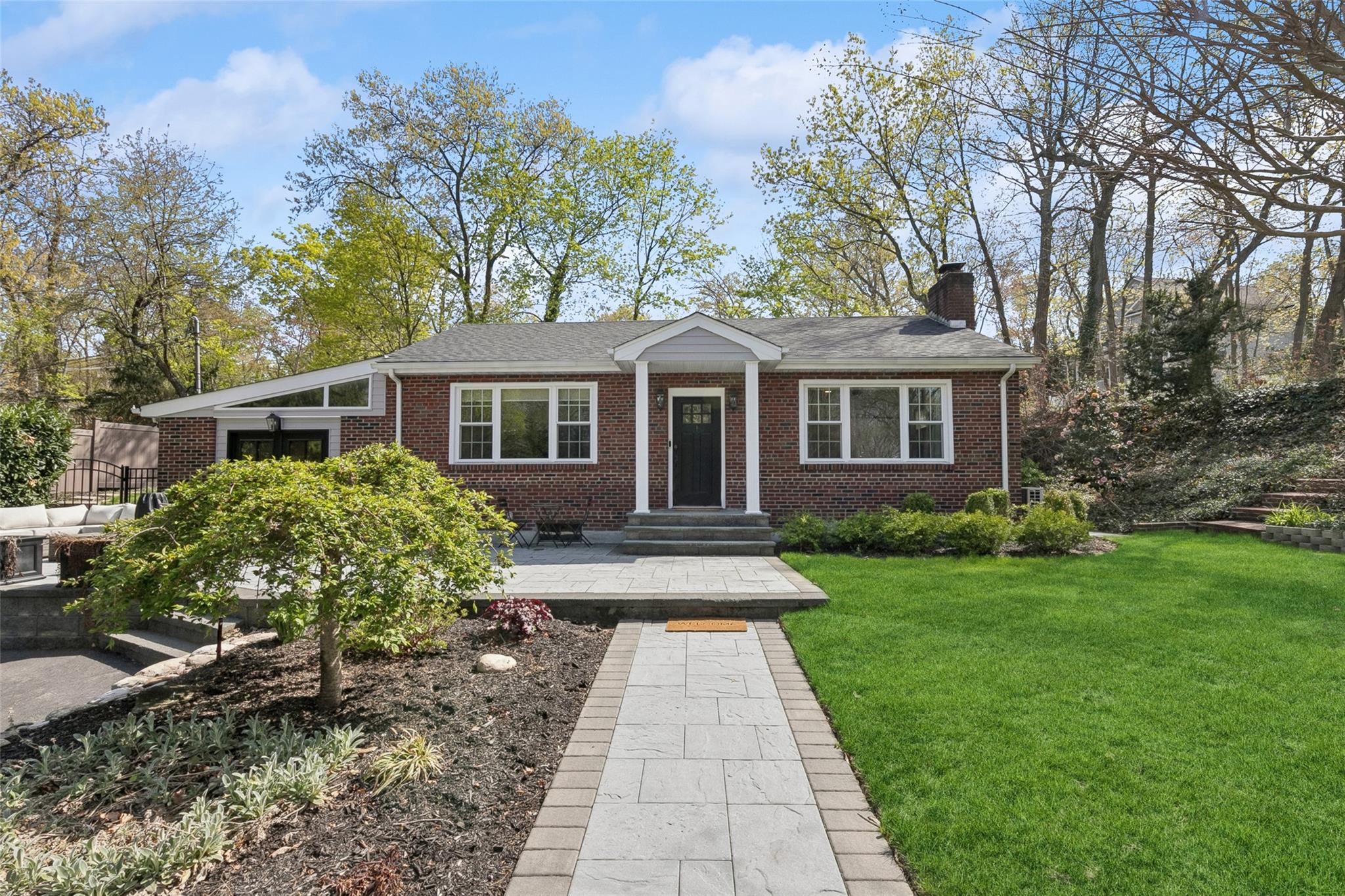 View of front of house with brick siding, a front yard, and a chimney