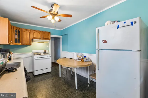 a white kitchen with a refrigerator a stove a dining table and chairs