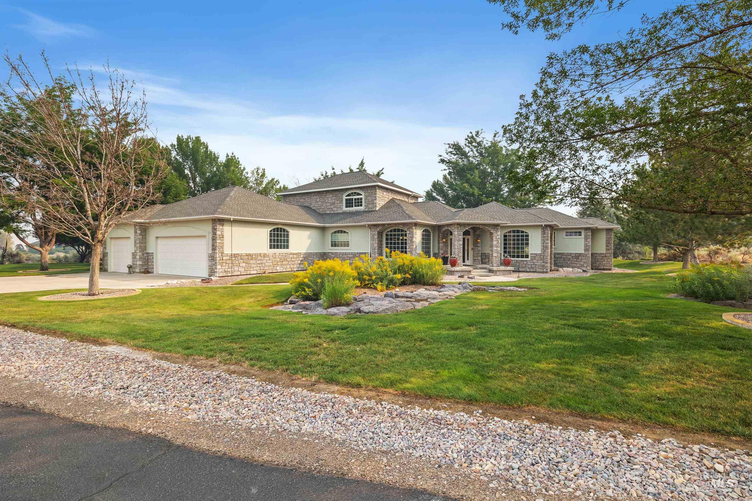 3404 Ridge Line Drive Kimberly, ID 83341 - Photo 46 of 50 Expansive property featuring a stone and stucco exterior, multiple arched windows, a multi-car garage, and a lush green lawn