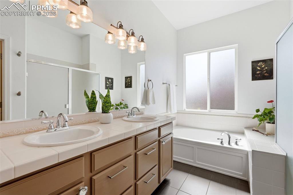 10744 Rhinestone Drive Colorado Springs, CO 80908 - Photo 24 of 50 a bathroom with a tub a double vanity sink and a mirror