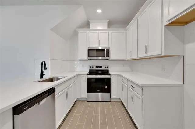 a kitchen with granite countertop a sink stove and microwave