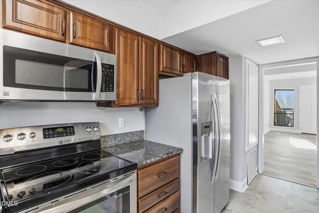 a kitchen with stainless steel appliances granite countertop a refrigerator and a stove top oven