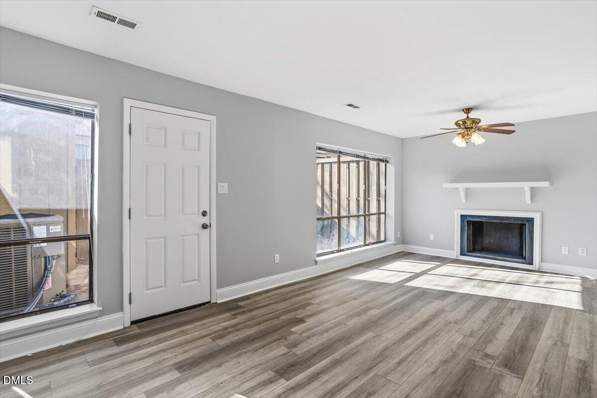 5021 Tall Pines Court Raleigh, NC 27609 - Photo 15 of 30 wooden floor fireplace and windows in an empty room