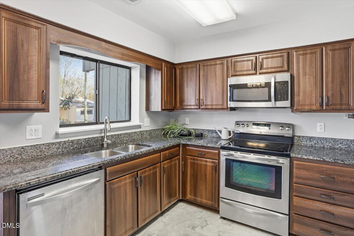 5021 Tall Pines Court Raleigh, NC 27609 - Photo 8 of 30 a kitchen with granite countertop a sink and a stove top oven