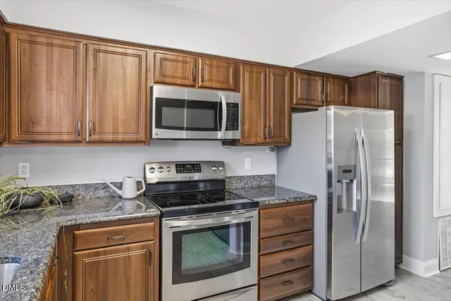 a kitchen with granite countertop a refrigerator stove and microwave