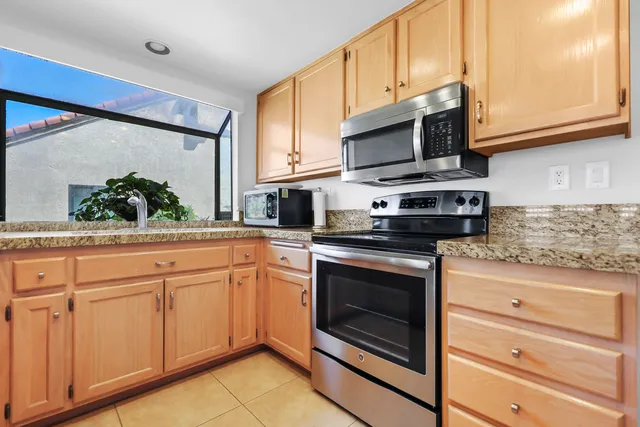 a kitchen with stainless steel appliances granite countertop white cabinets granite counter tops and a wooden floors