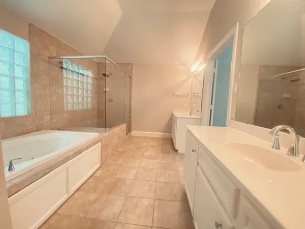 a spacious bathroom with a tub sink and mirror