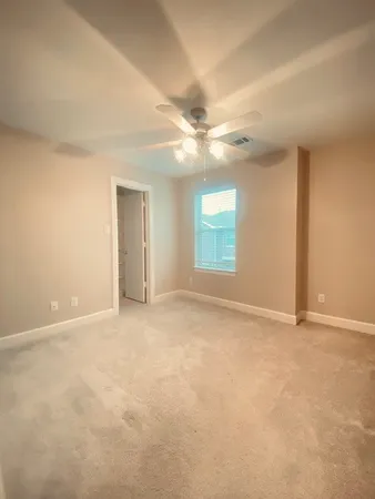 an empty room with windows and ceiling fan