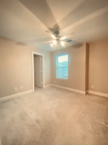 an empty room with windows and ceiling fan