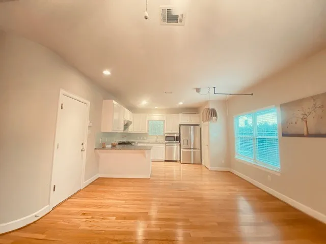 a view of a kitchen with a sink and dishwasher a refrigerator with white cabinets