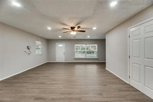 an empty room with windows and ceiling fan