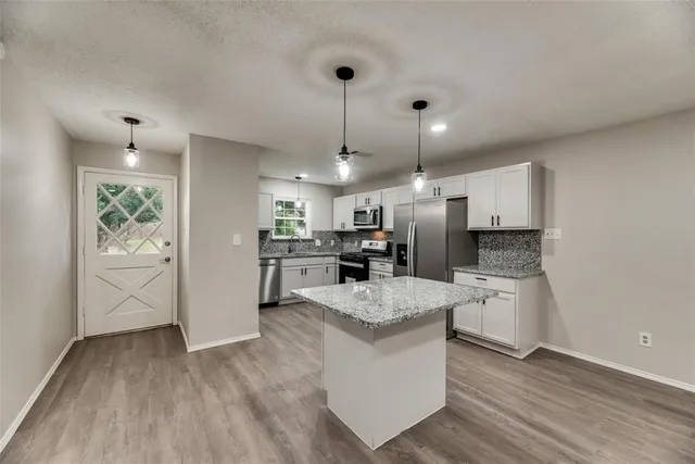 a large white kitchen with a refrigerator a sink dishwasher a stove and white cabinets with wooden floor