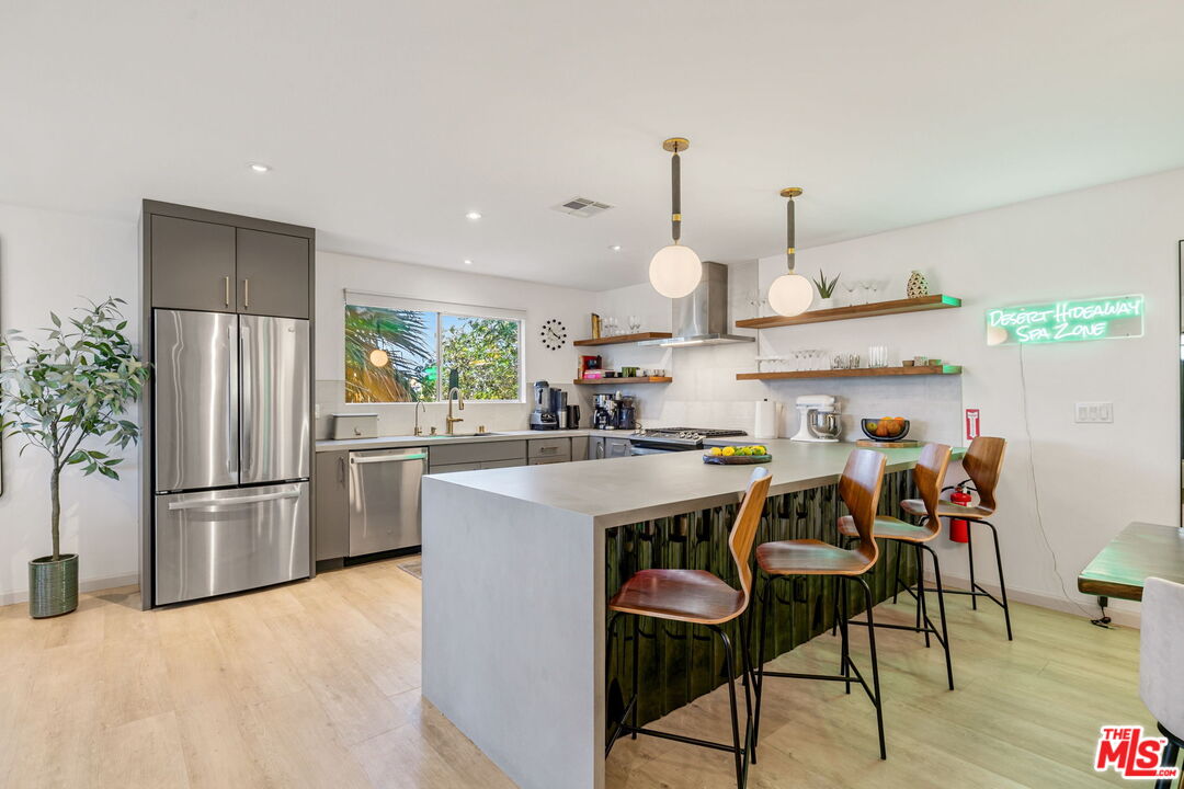 66869 San Ardo Road Desert Hot Springs, CA 92240 - Photo 14 of 39 a open kitchen with stainless steel appliances granite countertop a sink a stove a refrigerator and island with wooden floor