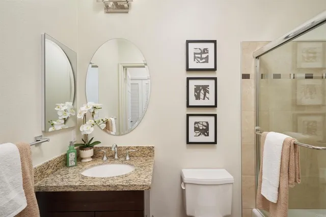 a bathroom with a granite countertop toilet sink and mirror