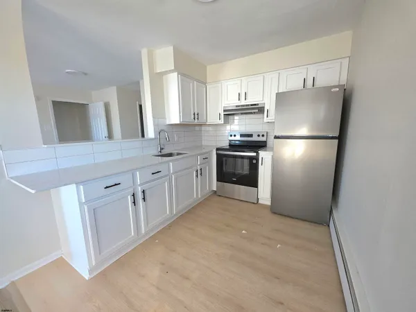 a kitchen with white cabinets stainless steel appliances and a refrigerator