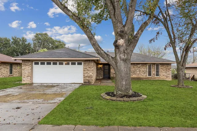 a view of a house with a yard and large tree