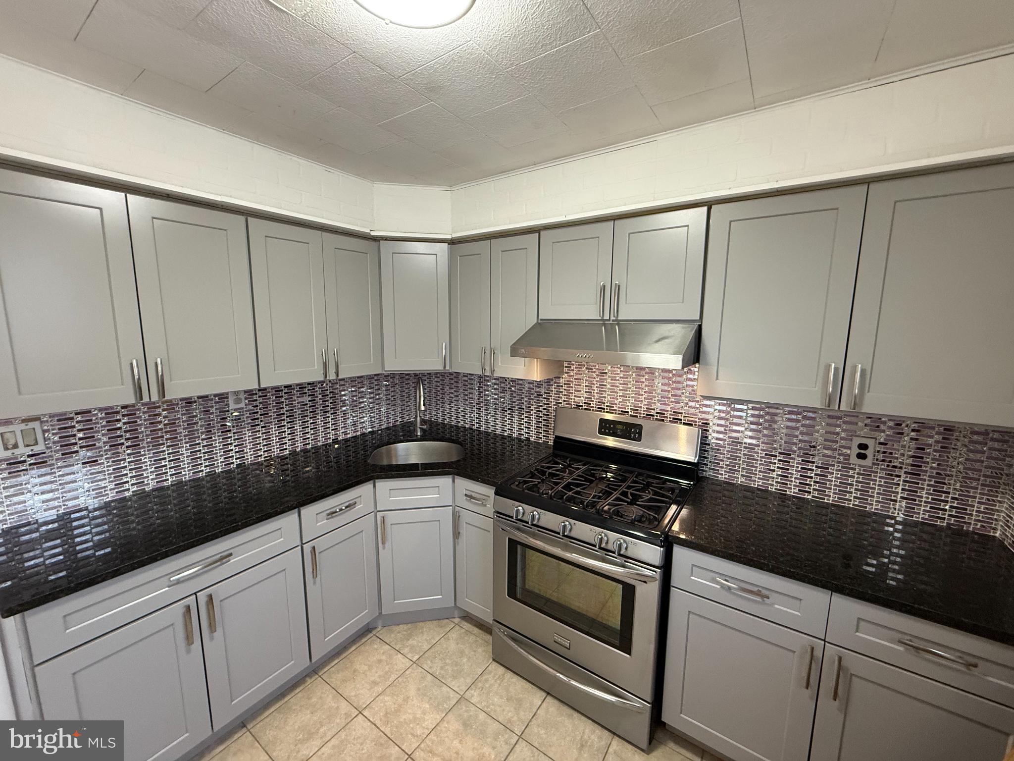 7735 Loretto Avenue Philadelphia, PA 19111 - Photo 9 of 19 a kitchen with granite countertop white cabinets and black appliances