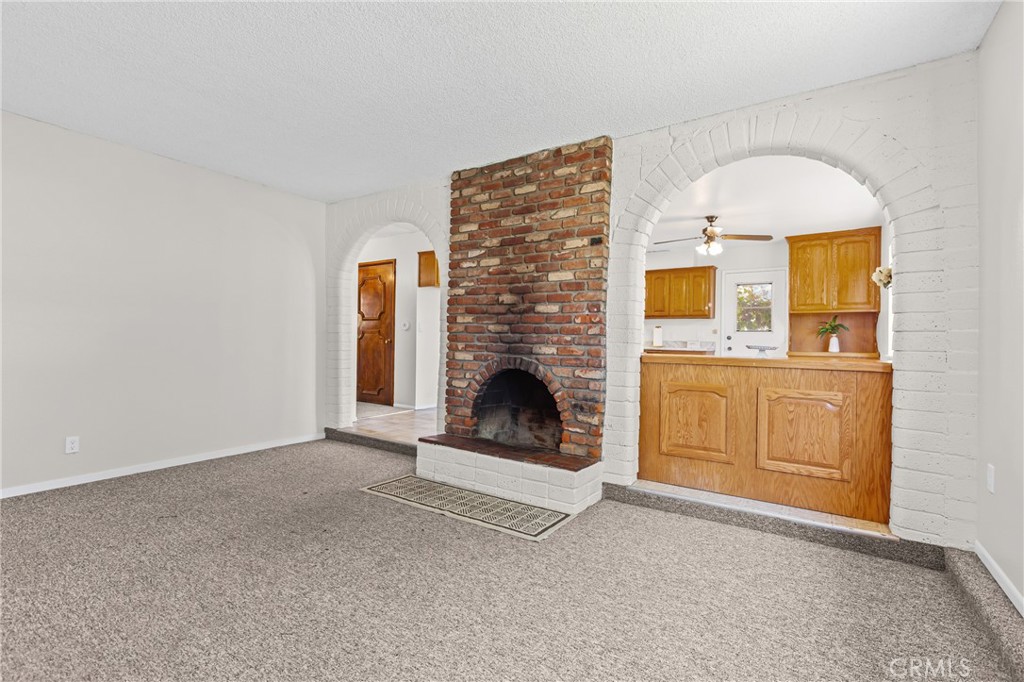 735 Orchard Road Nipomo, CA 93444 - Photo 4 of 49 Cozy living room with wood-burning fireplace, and beautiful brick archways that lead into the kitchen and dining area.
