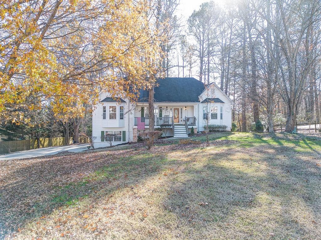 a front view of a house with a yard and large trees