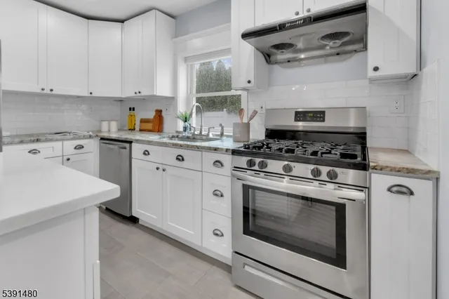 a kitchen with cabinets stainless steel appliances and wooden floor