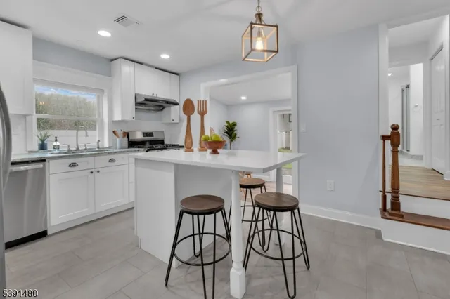 a kitchen with stainless steel appliances kitchen island granite countertop a sink a stove a refrigerator cabinets and dining table