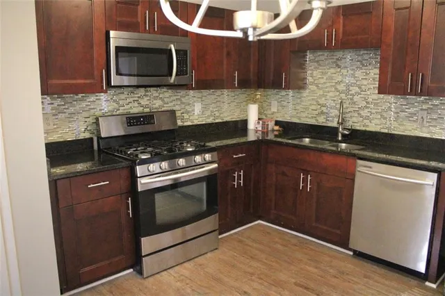a kitchen with stainless steel appliances granite countertop a stove microwave and sink