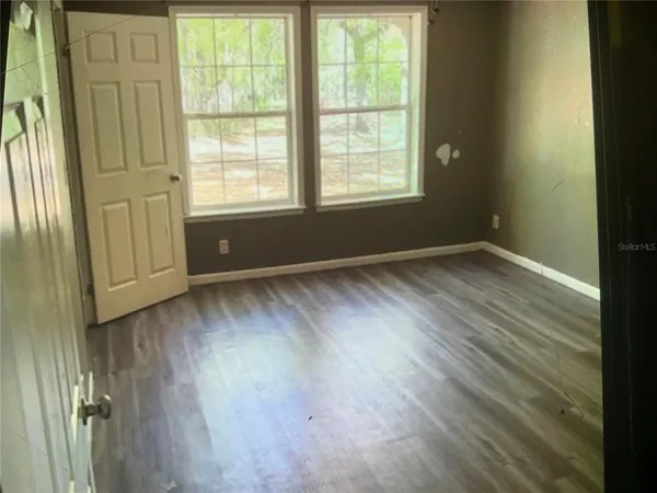 an empty room with wooden floor and windows