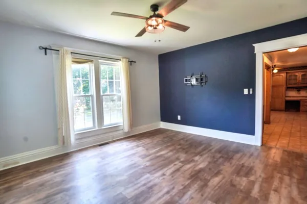 a view of an empty room with window wooden floor and a ceiling fan