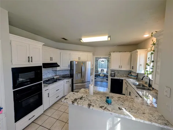 a kitchen with stainless steel appliances kitchen island granite countertop a refrigerator stove top oven and sink