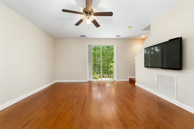 a view of an empty room with wooden floor and a window
