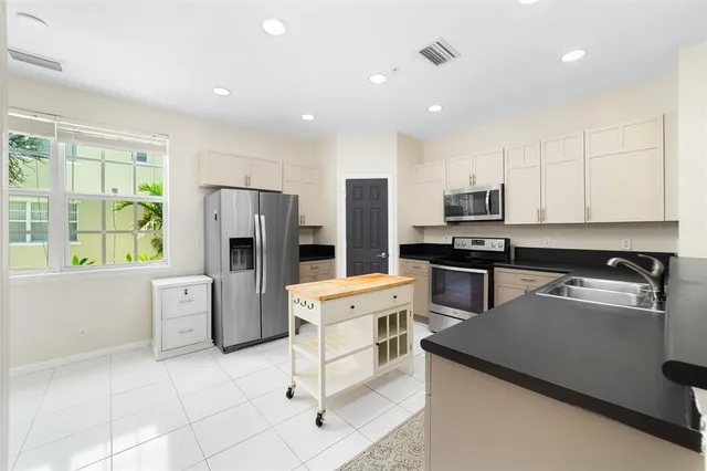 a kitchen with a refrigerator a stove a sink a center island and furniture