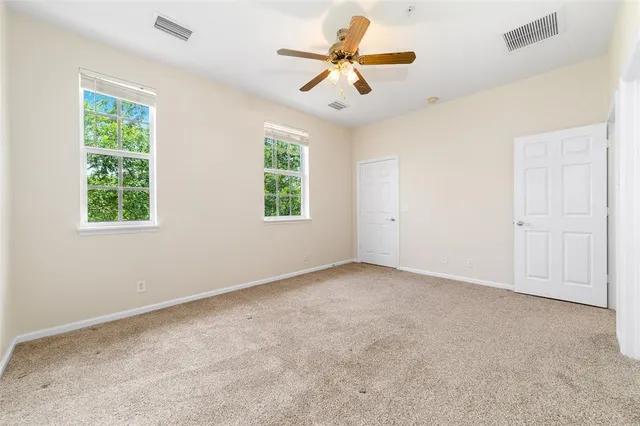 an empty room with windows and chandelier fan