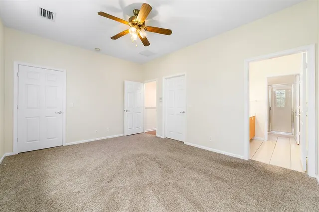 an empty room with closet and a chandelier fan